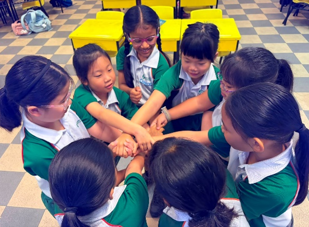 Students joining hands during a classroom team-building activity.